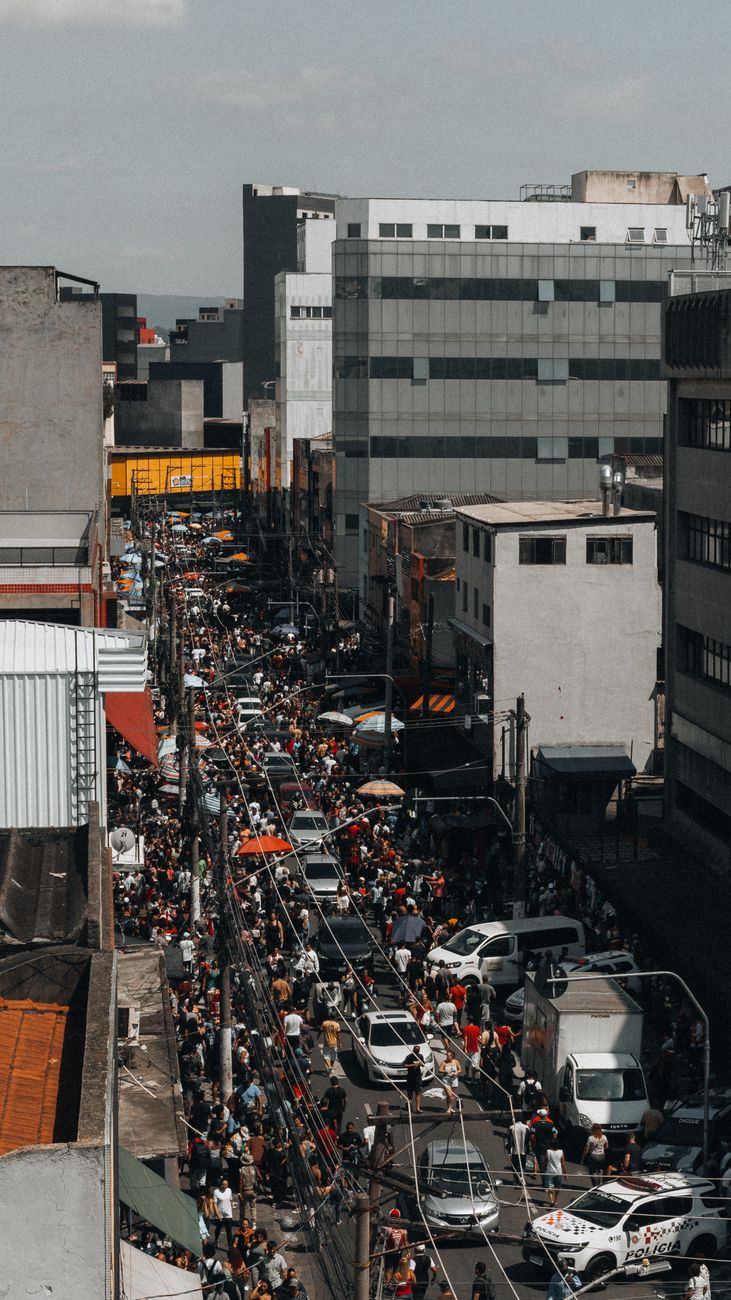 A bustling city street filled with people and vehicles on a sunny day.