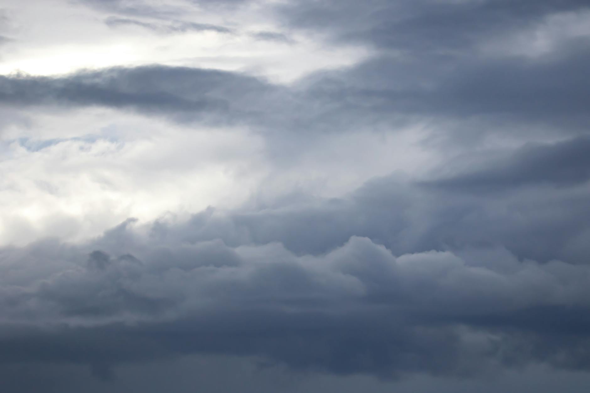 A dramatic view of a moody, overcast sky filled with dark clouds and a hint of light piercing through.