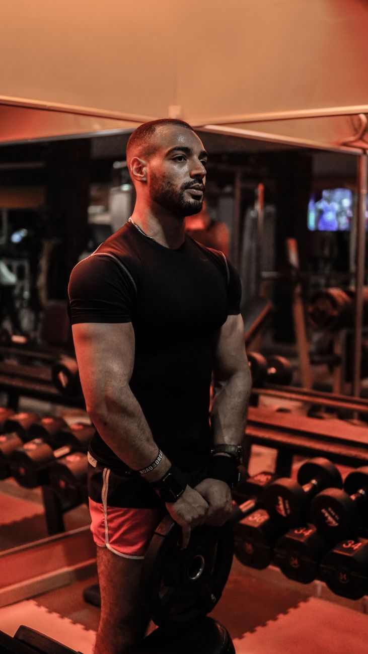 Man training with weights indoors. Focused expression, gym setting, fitness concept.