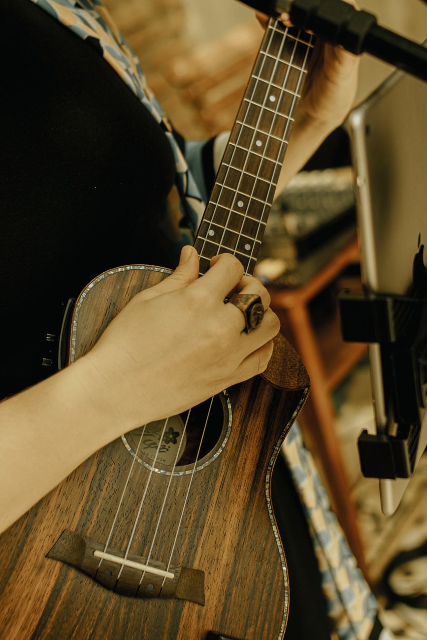 A woman softly strums a ukulele indoors, creating a cozy and artistic mood.