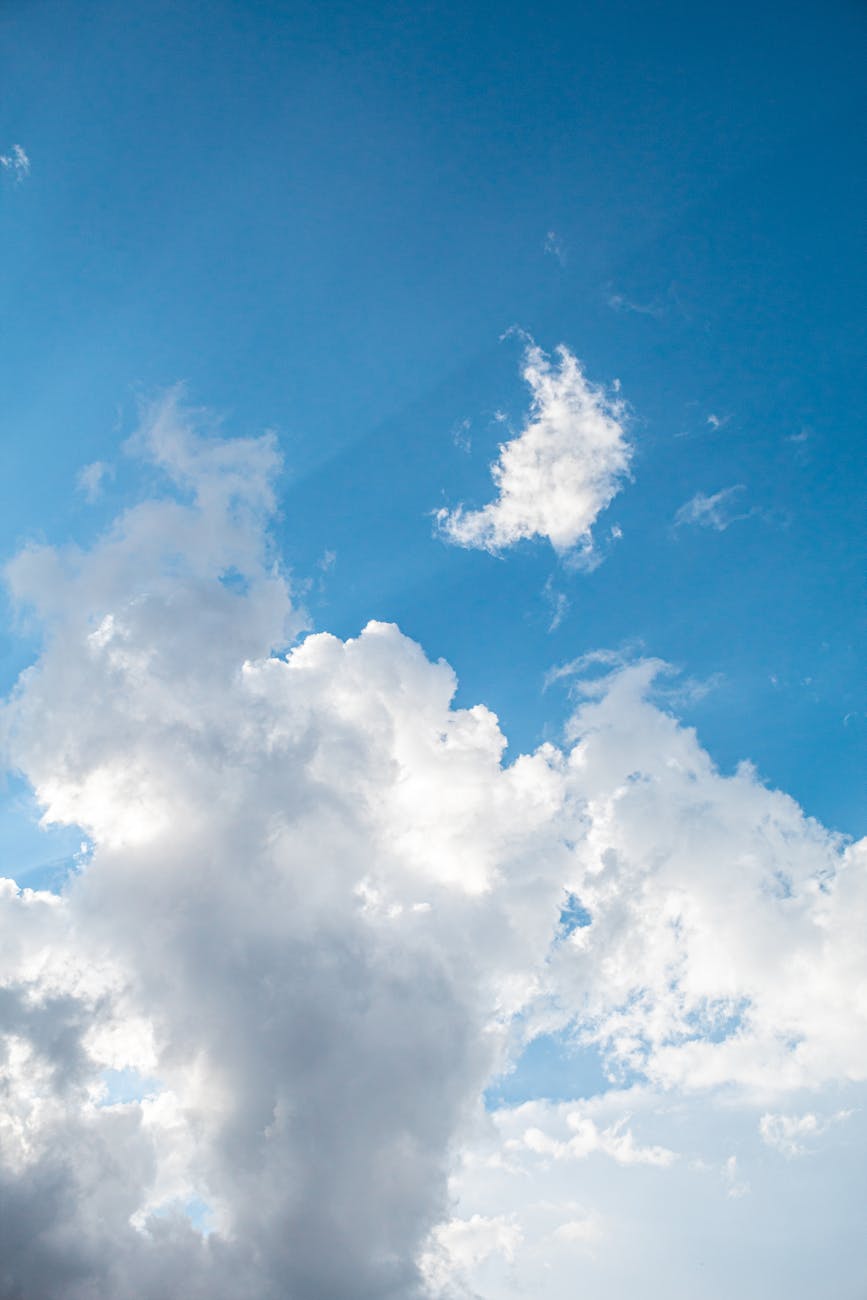 A clear blue sky featuring large, fluffy cumulus clouds on a sunny day.
