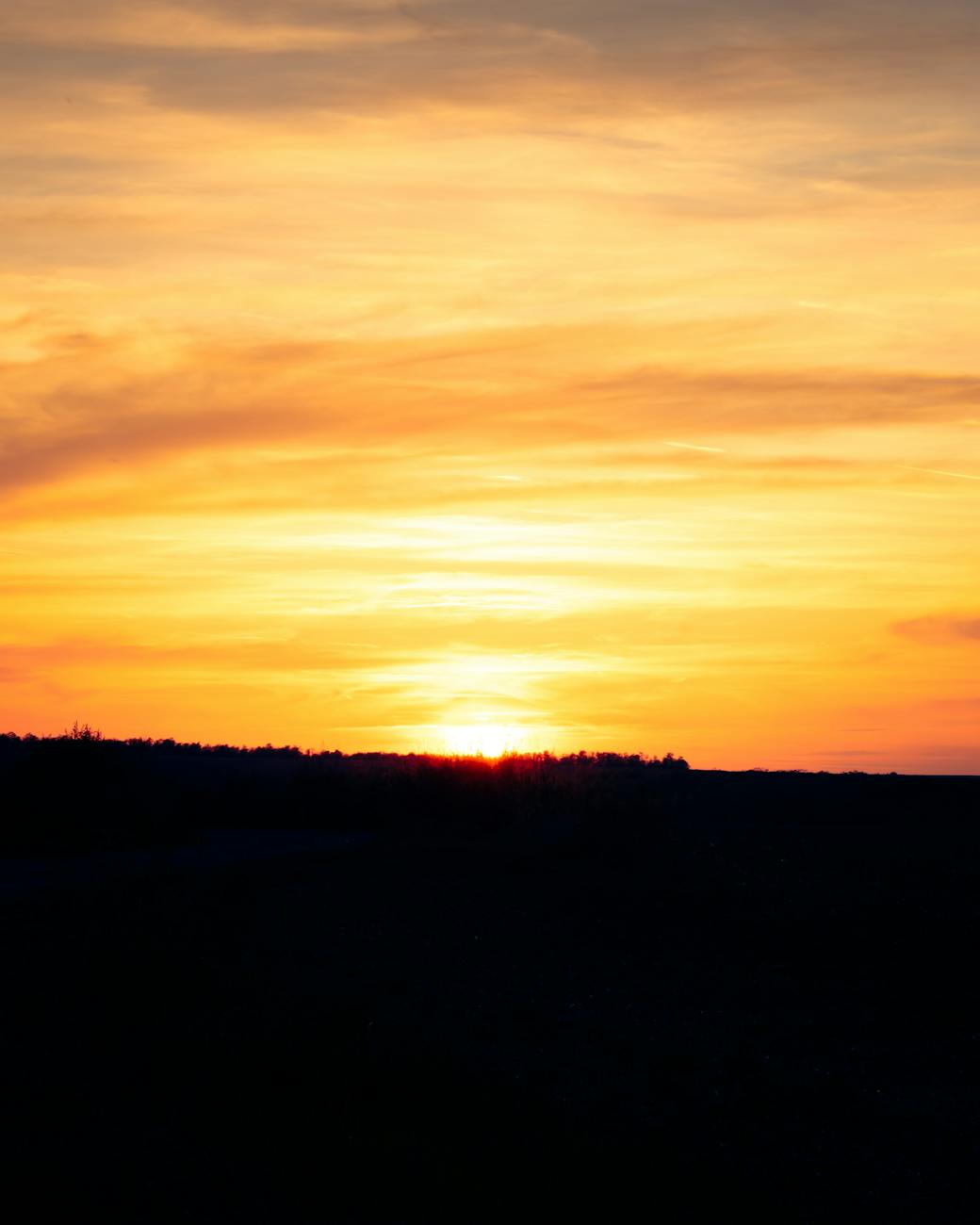 Captivating sunset with vivid orange hues over serene hills, perfect for nature lovers.