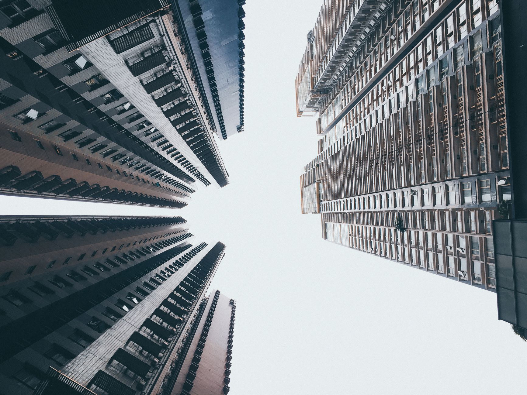 A striking low-angle perspective of Hong Kong skyscrapers reaching toward a bright sky.