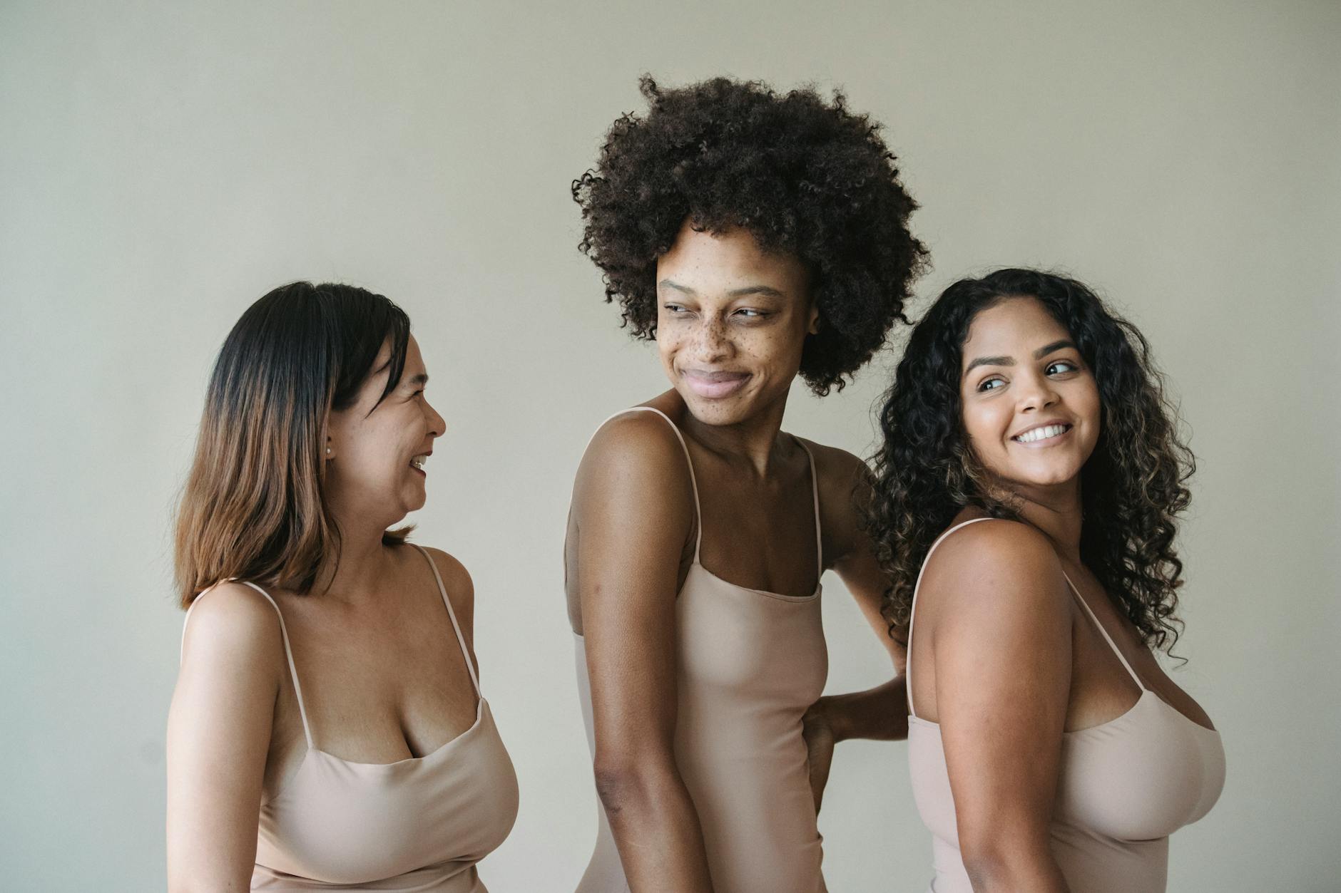 Celebrating body positivity and diversity with women posing confidently in neutral-toned fashion.