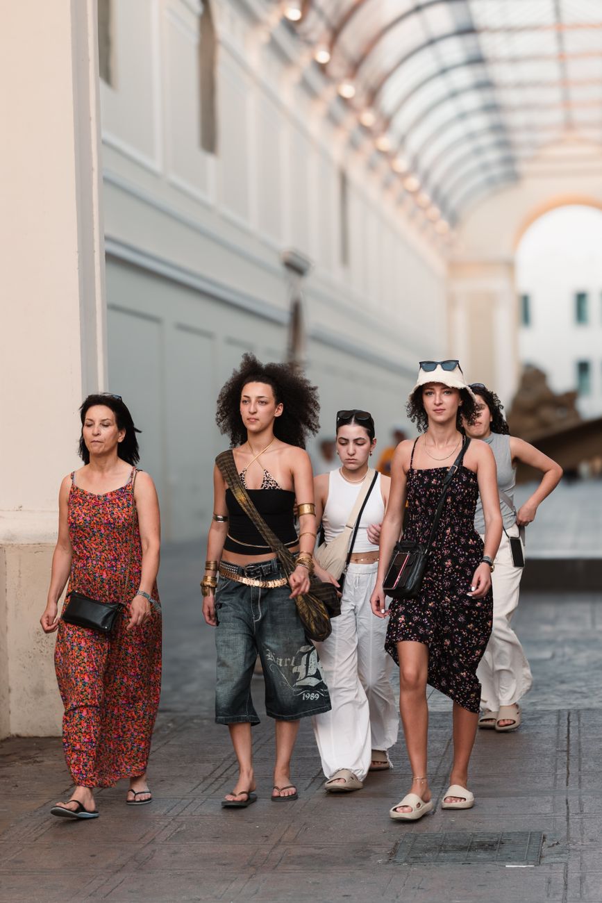 A group of women walking through a stylish urban shopping arcade, showcasing casual summer fashion.