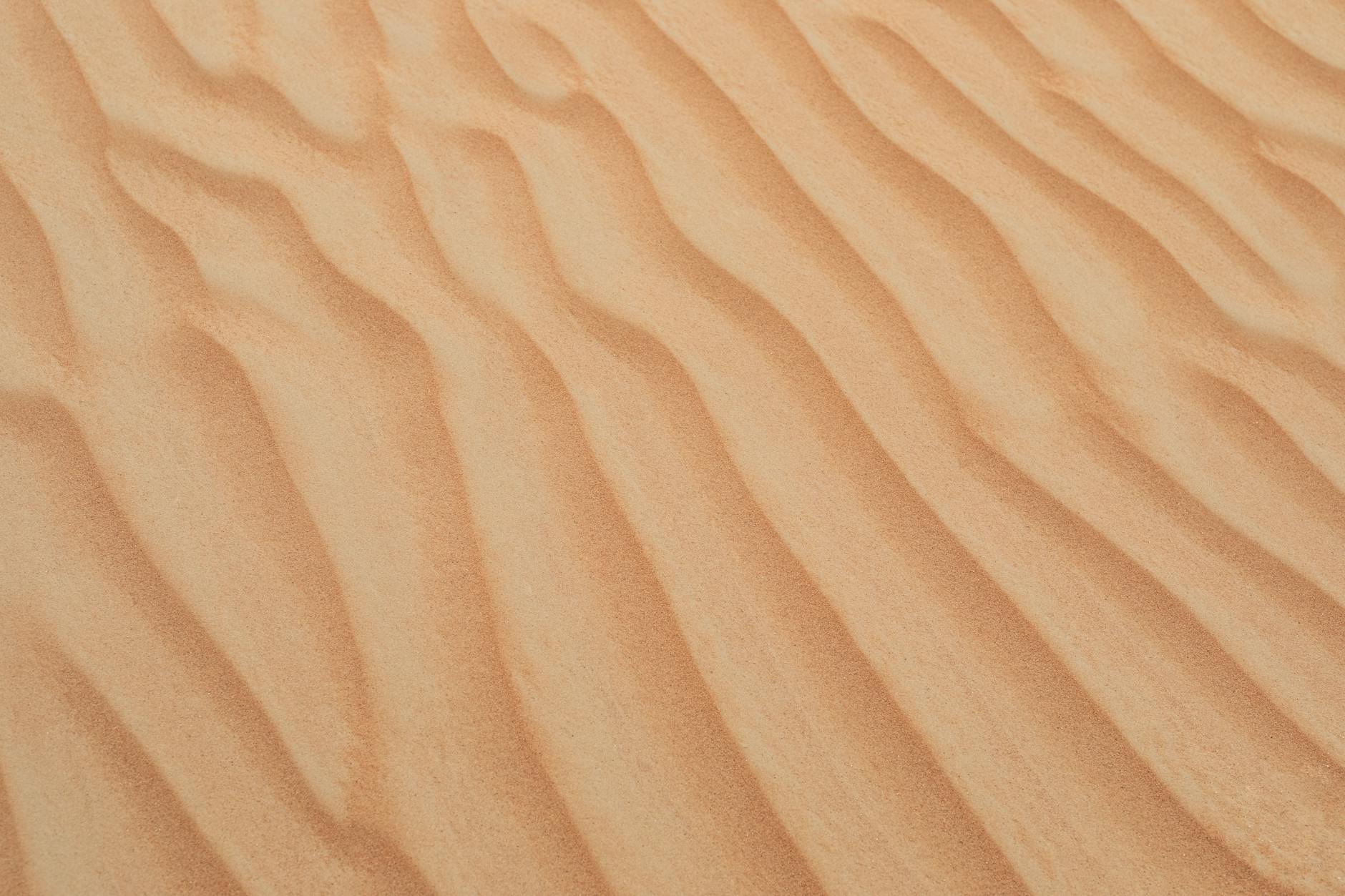 A serene view of golden sand dunes with smooth textures in Dubai's desert, perfect for backgrounds and wallpapers.