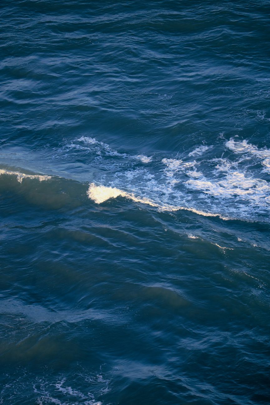High-angle view of ocean waves with deep blue water, capturing a serene and natural sea scene.