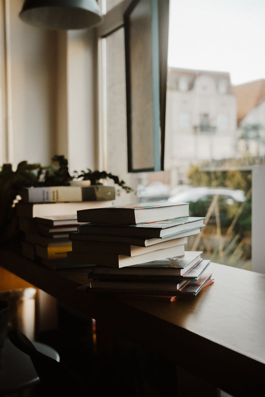 A serene indoor scene with books stacked by a window, perfect for study or relaxation.
