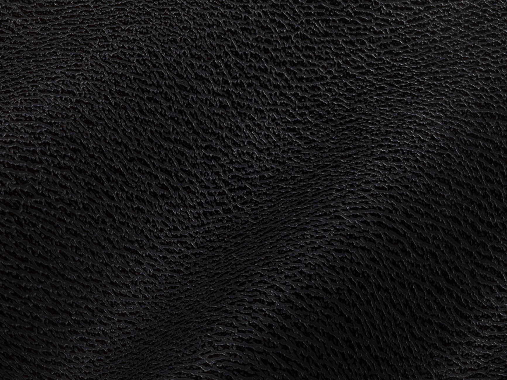 Close-up of black leather texture with detailed grain and subtle folds.