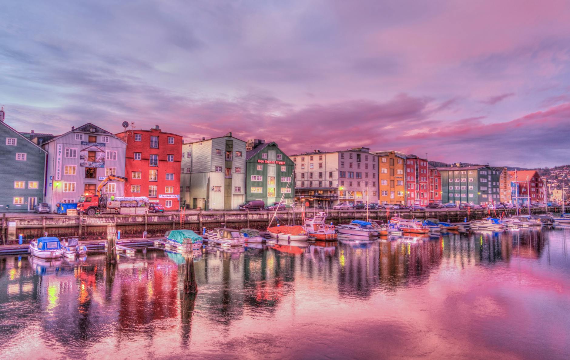 Vibrant waterfront scene with colorful buildings and boats reflecting in the water at sunset.
