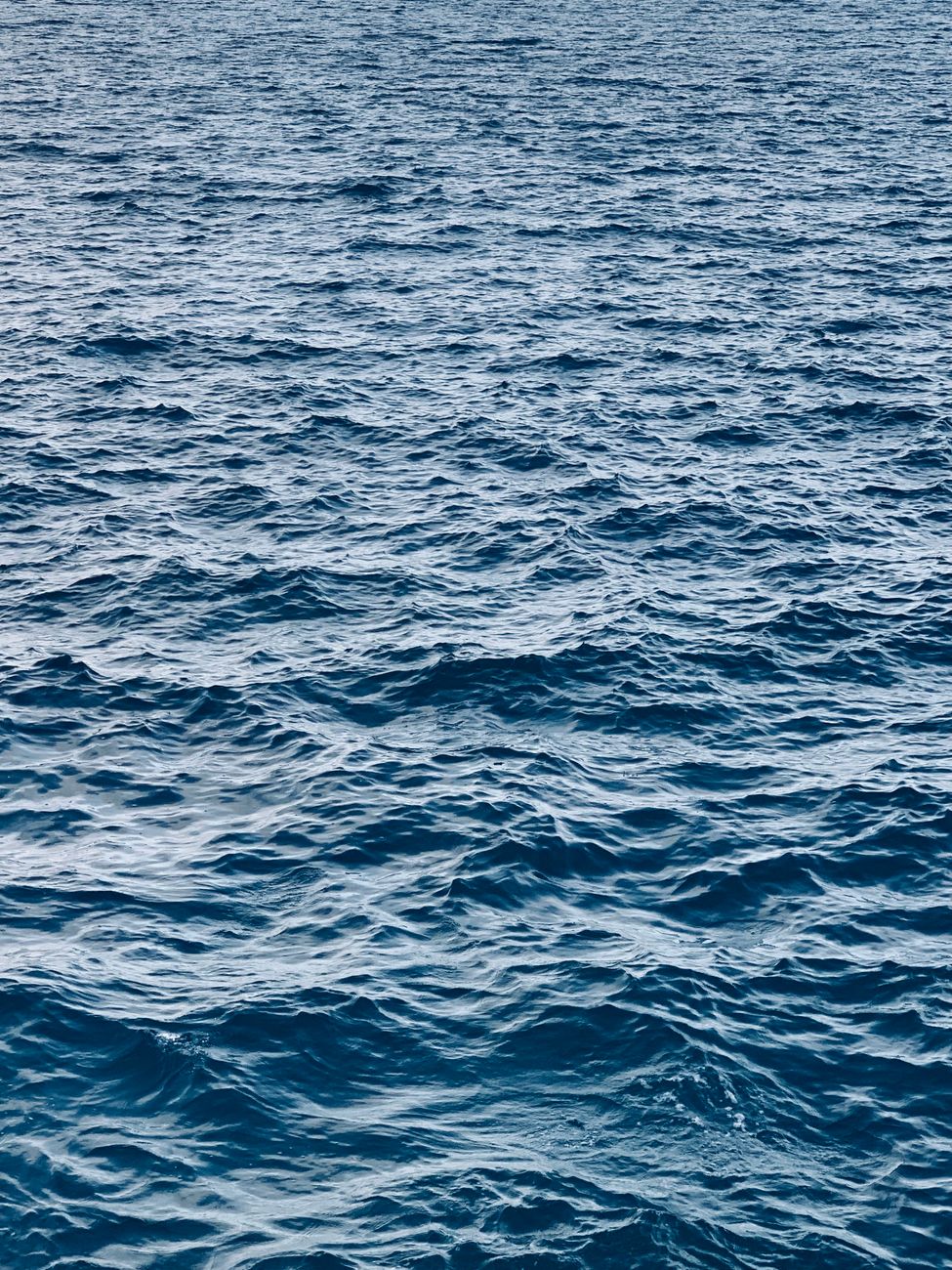 A serene seascape with wavy textures on the deep blue ocean surface.