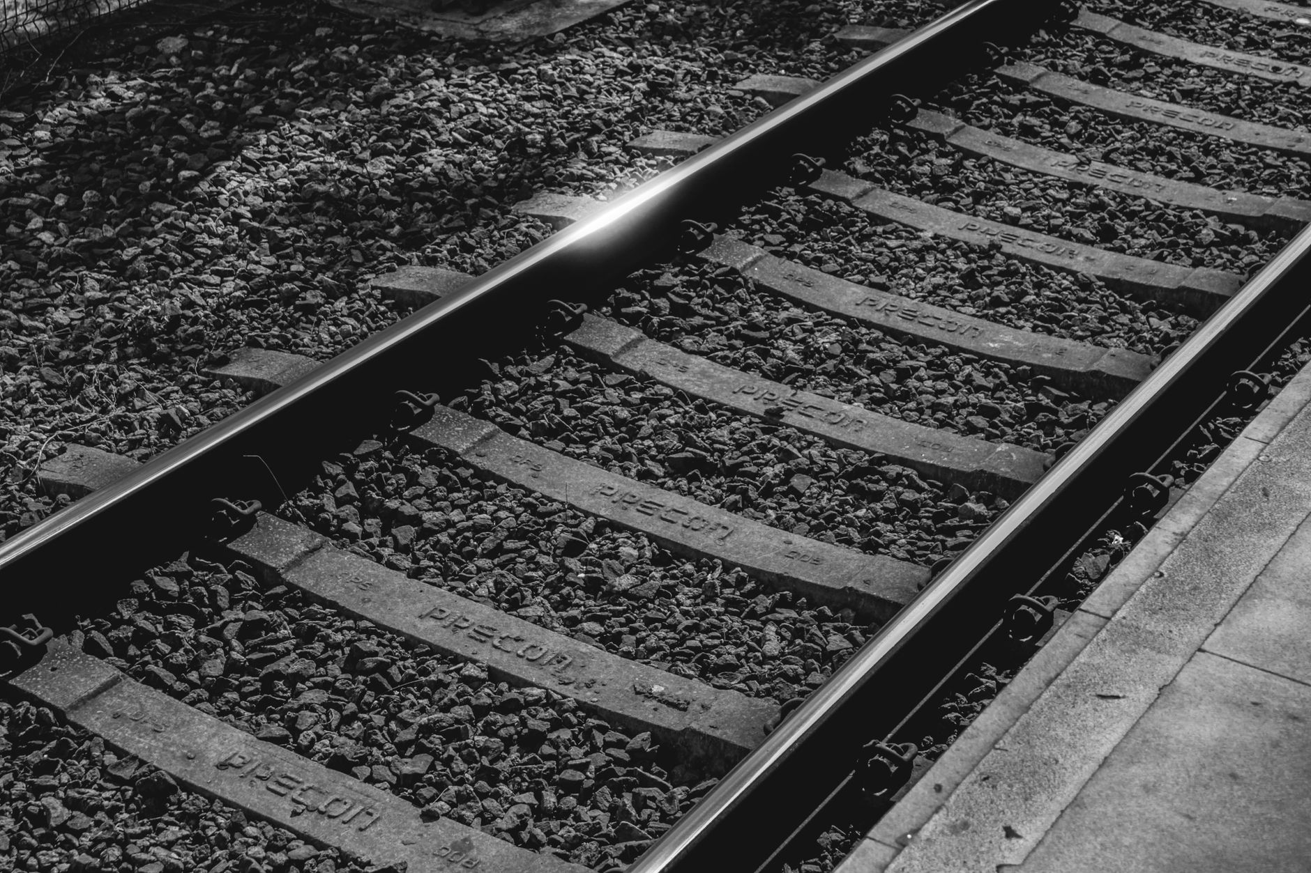 Detailed black and white view of railway tracks with gravel and sleepers.