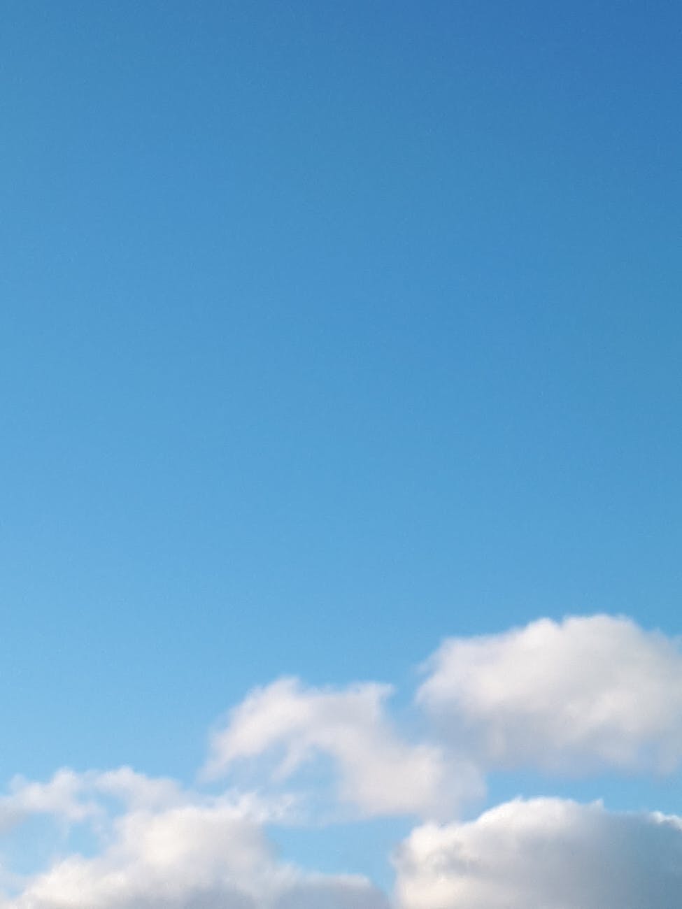 A serene blue sky with soft white clouds, perfect for nature backgrounds and relaxation themes.