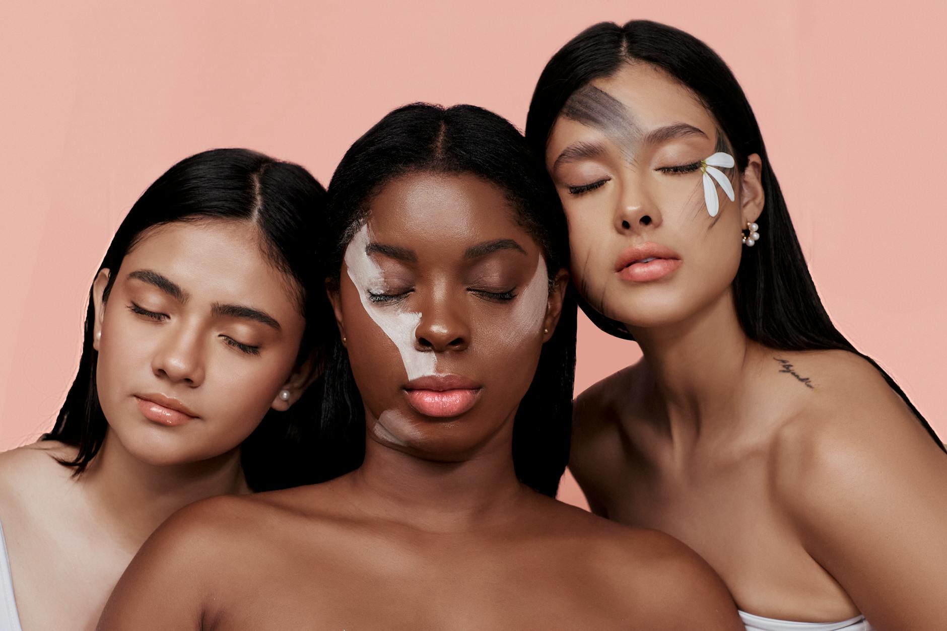 Three women embracing diversity with artistic makeup in a studio portrait.