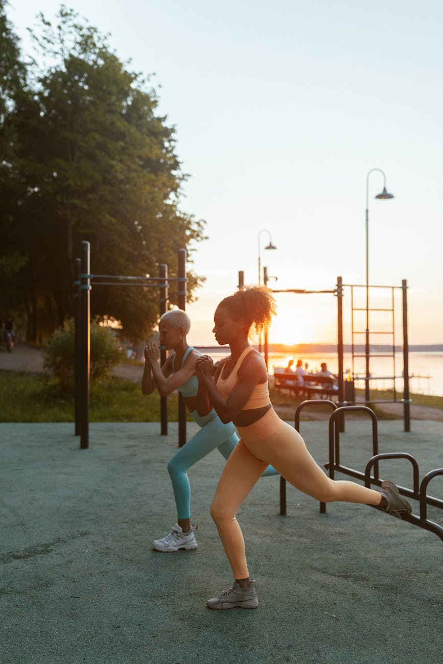 Two women exercising outdoors at sunset, demonstrating fitness and health.