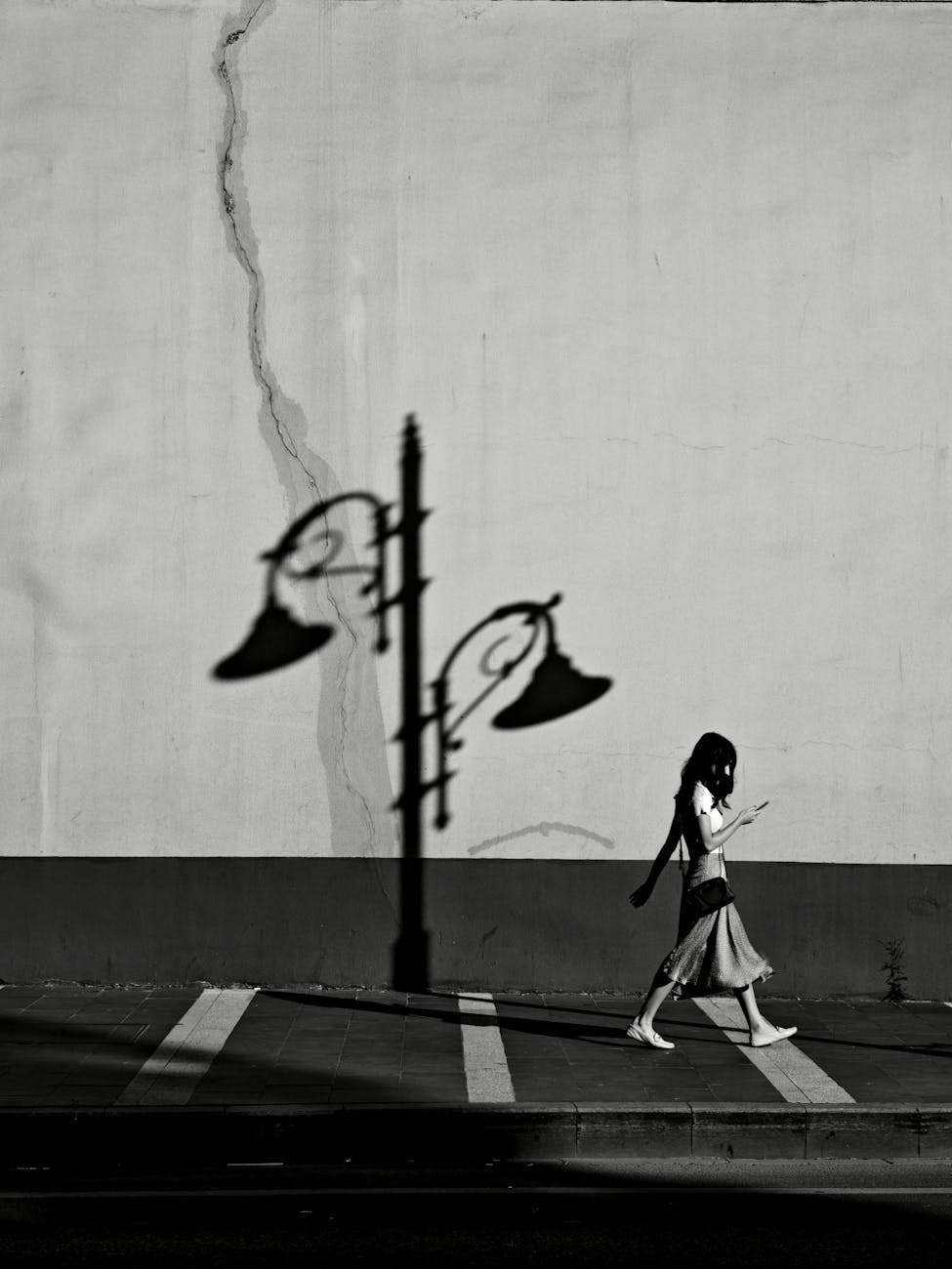 Artistic black and white photo capturing a silhouette walking by a streetlamp shadow in Istanbul, Türkiye.