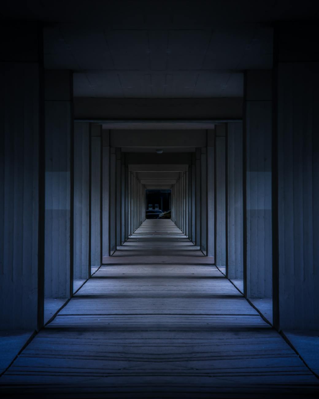 A dramatic view of a modern hallway with symmetrical columns creating an infinite perspective.