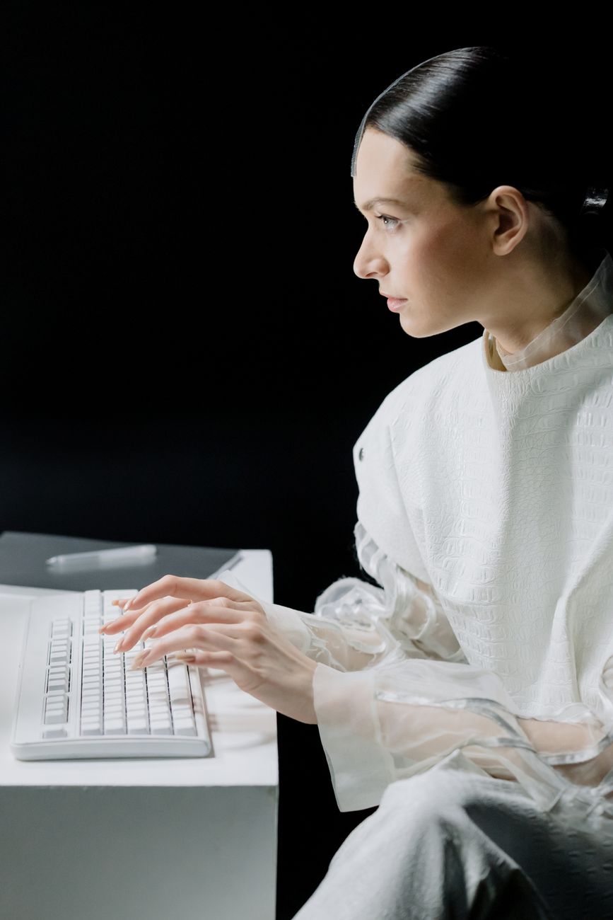 Side view of a woman typing on a keyboard, focused on work in a modern office setting.