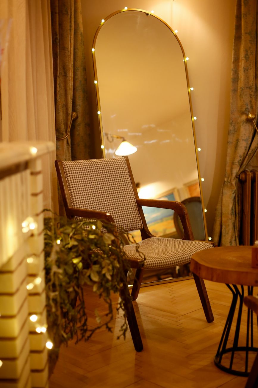 Warm living room featuring a stylish armchair and illuminated mirror, creating a serene atmosphere.