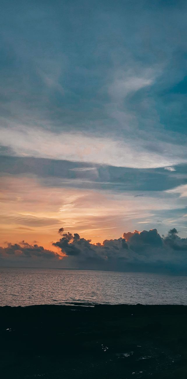 Peaceful sunset over the ocean with colorful clouds and tranquil sea view.