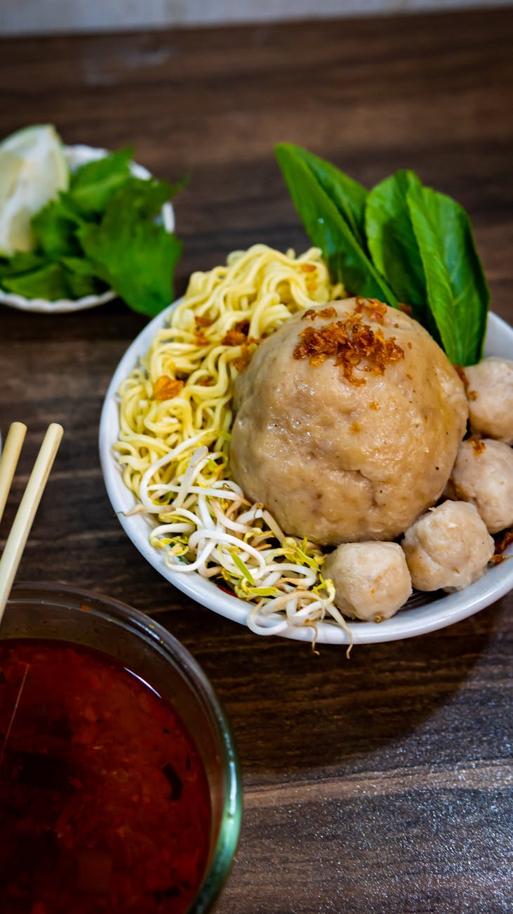 Delicious Indonesian bakso meatball dish with noodles, vegetables, and spicy sauce.