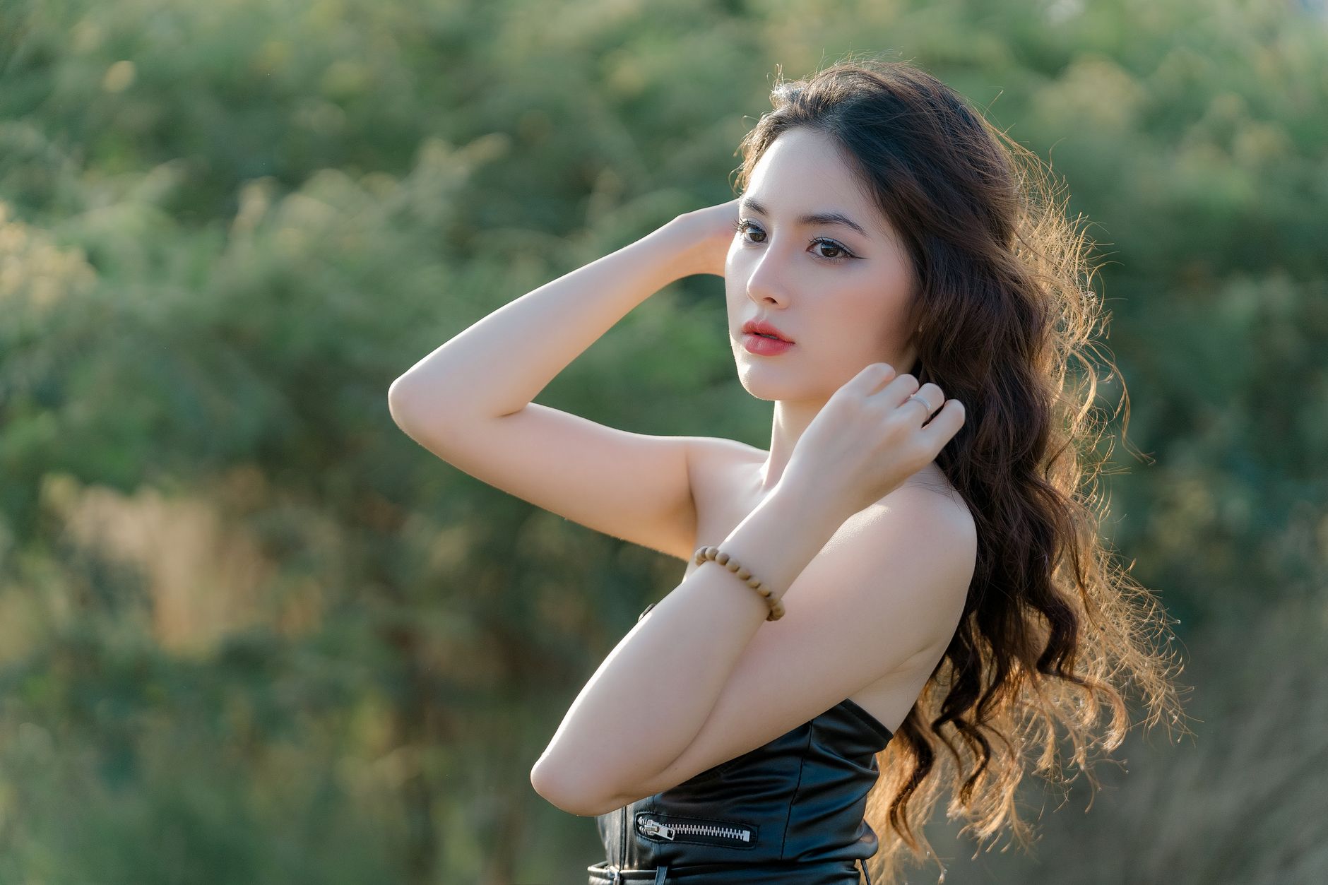Portrait of a woman with long hair and elegant dress captured outdoors in natural light, conveying a serene mood.