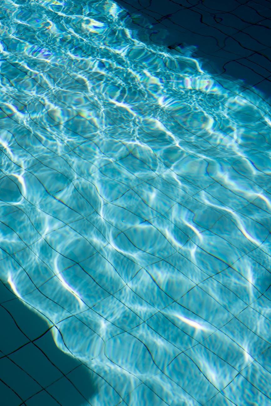 Sunlit ripples create a mesmerizing pattern in a clear pool, capturing light reflections.