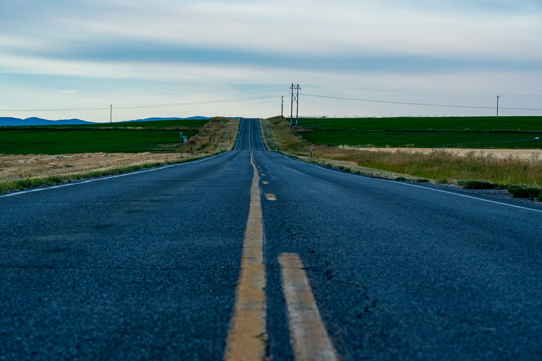 Peaceful rural road in Newton, Utah, surrounded by fields and open sky.