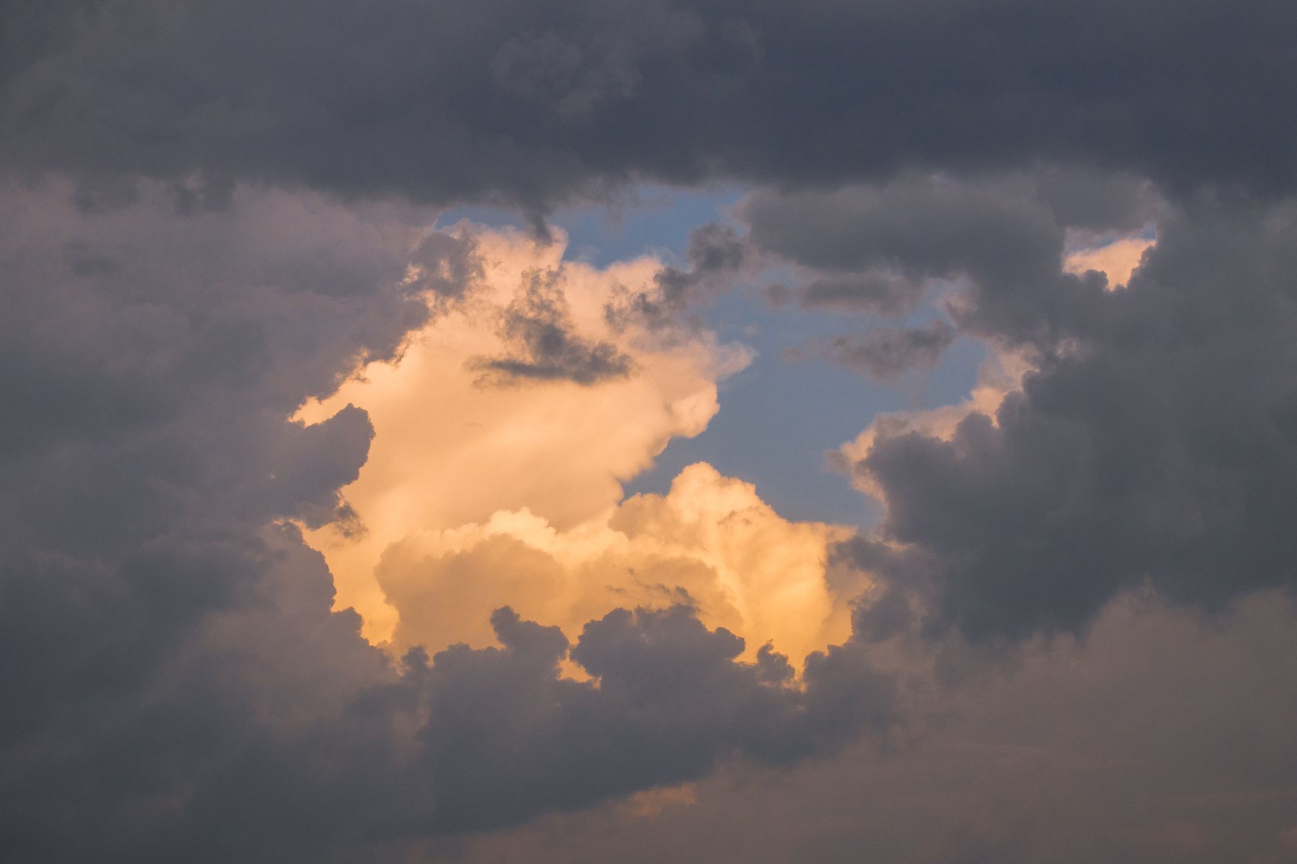 A captivating cloudscape featuring golden clouds illuminated by the setting sun, creating a serene and ethereal atmosphere.