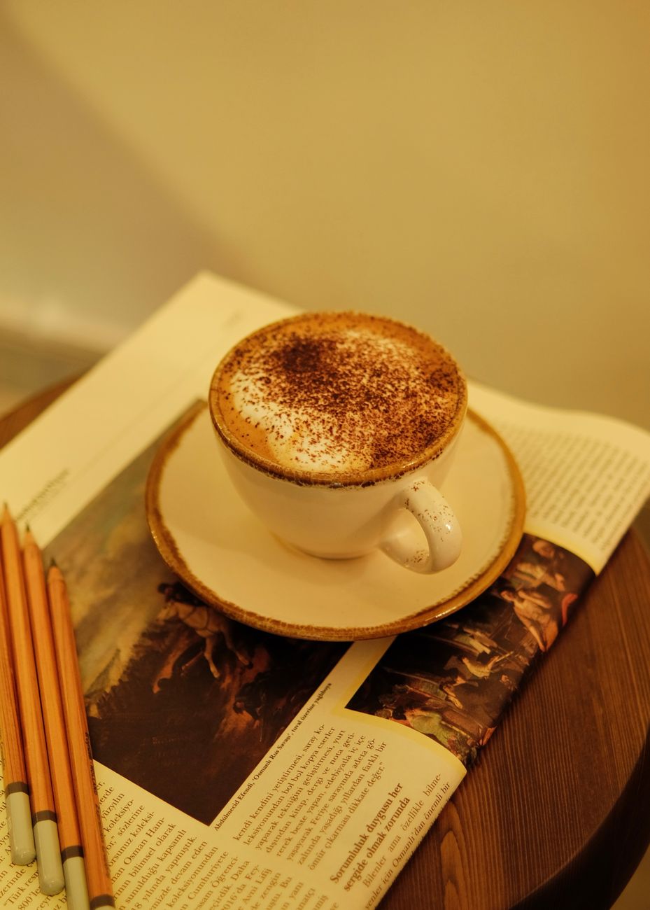 Warm cup of coffee resting on a magazine in a tranquil setting.