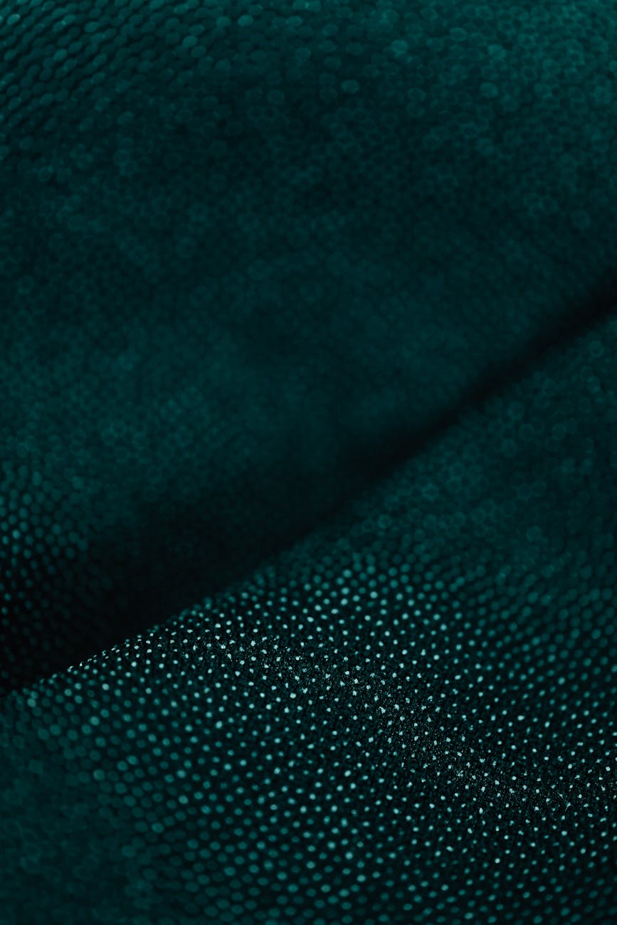 Detailed close-up of dark green fabric with a soft, textured pattern.