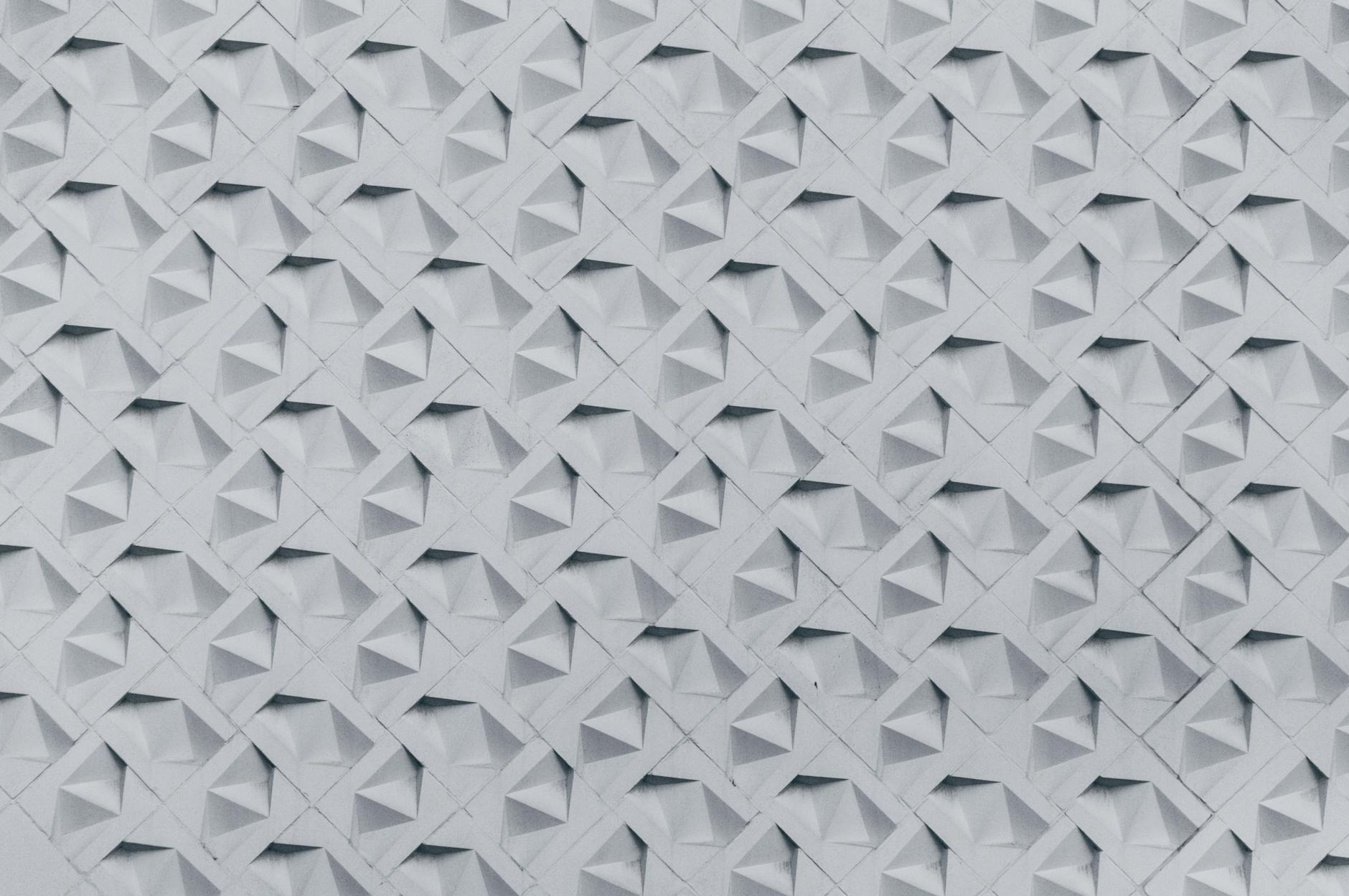Textured wall showcasing a geometric 3D pattern in monochrome tones, perfect for architectural inspiration.