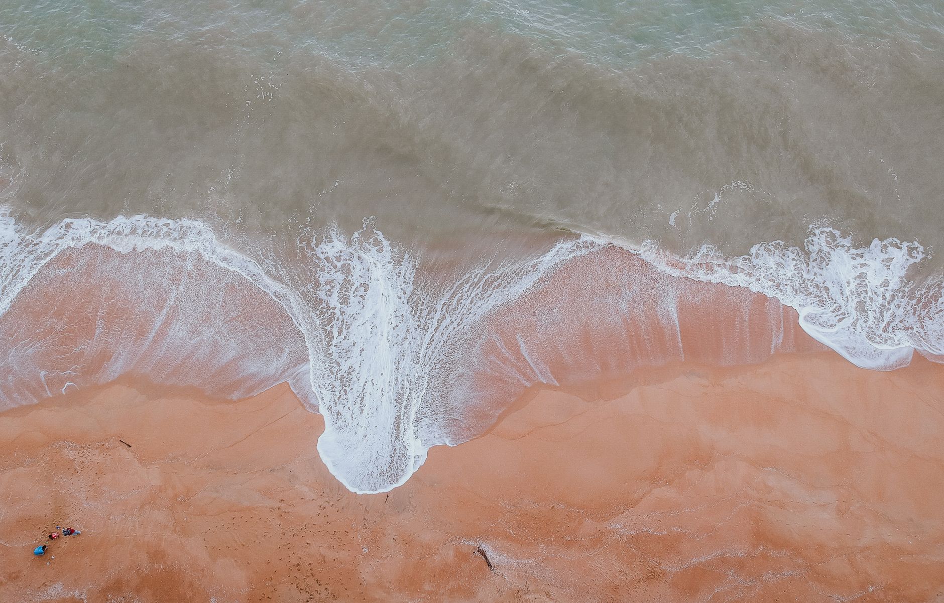 Captivating aerial view of ocean waves gently washing over a sandy beach, perfect for travel and nature themes.