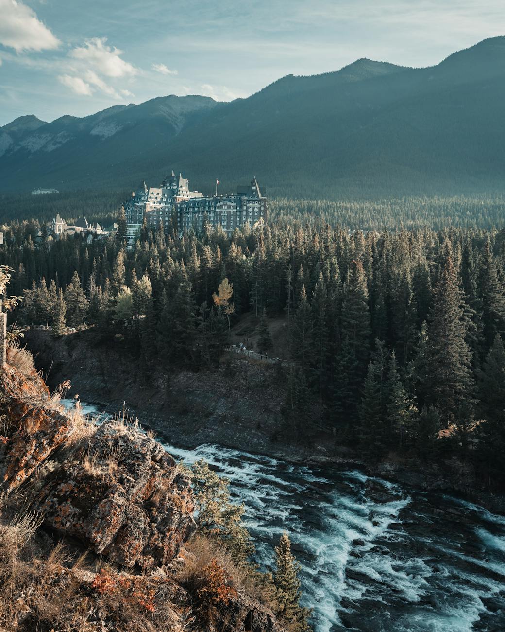 A beautiful view of Banff National Park featuring a distant lodge surrounded by lush forests and mountains.