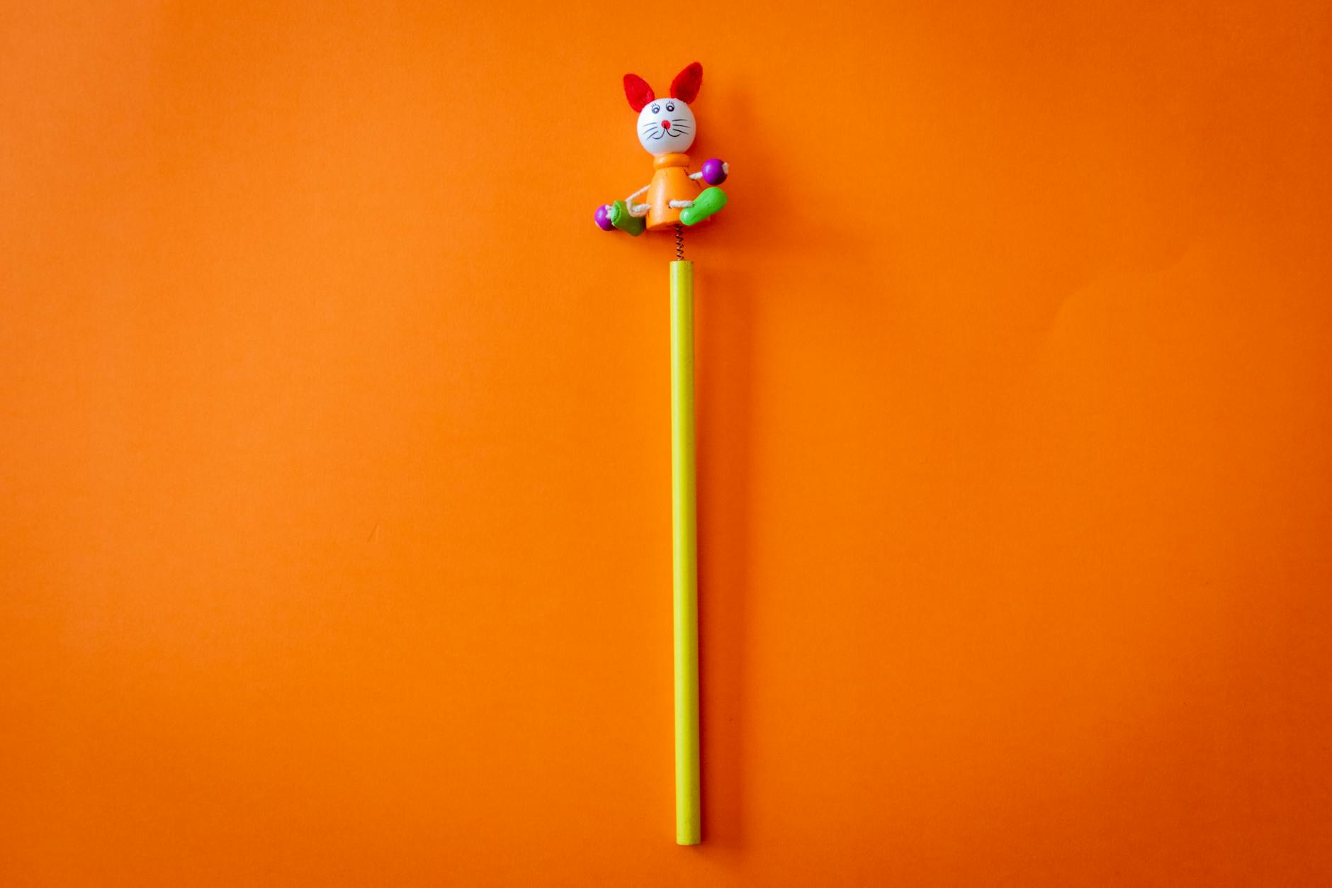 Brightly colored rabbit toy on a vibrant orange backdrop with ample copyspace.