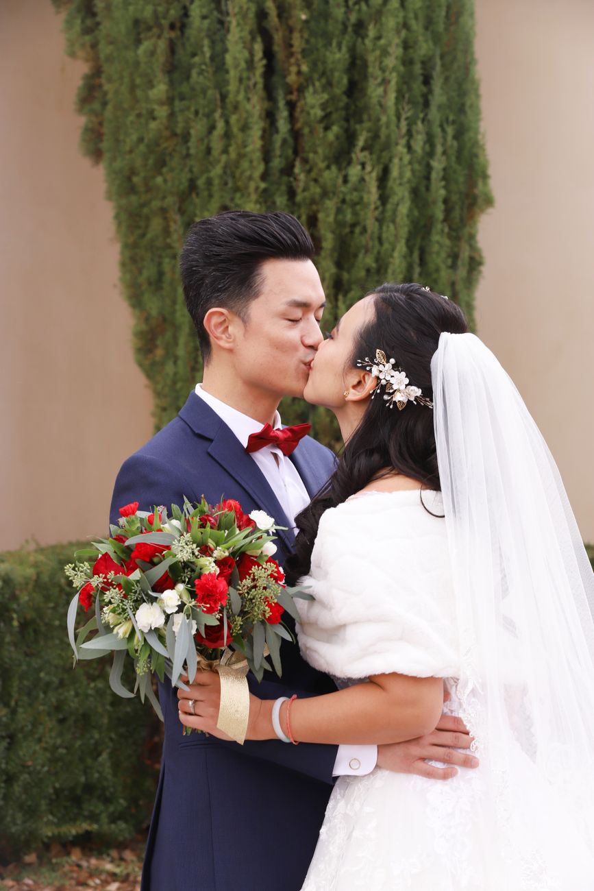 A couple shares a romantic kiss during their outdoor wedding ceremony.