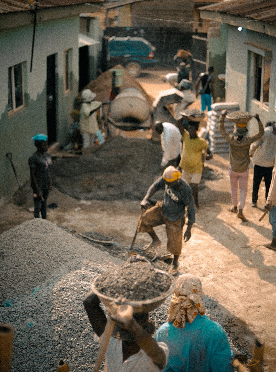 Aerial view of construction workers actively working on a site outdoors, carrying materials in bright sunlight.