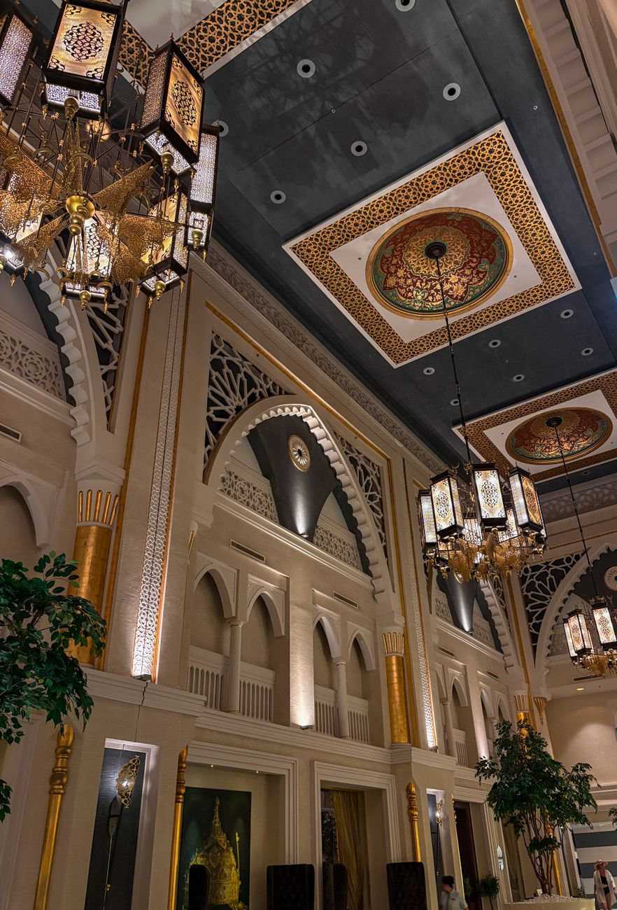 A lavish interior of a Dubai hotel featuring ornate ceiling designs, chandeliers, and grand architecture.