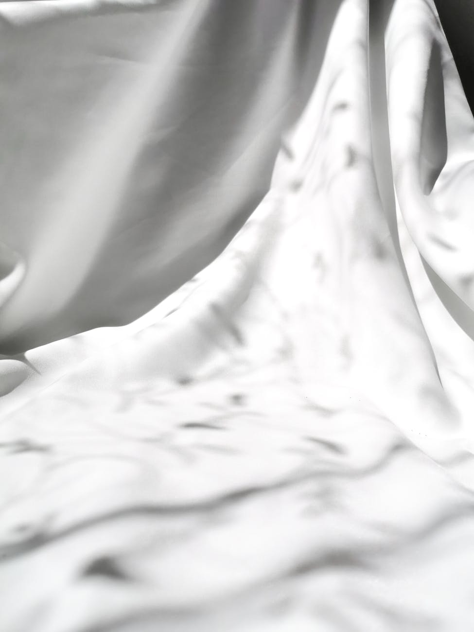 A flowing white fabric draped elegantly, casting soft shadows.