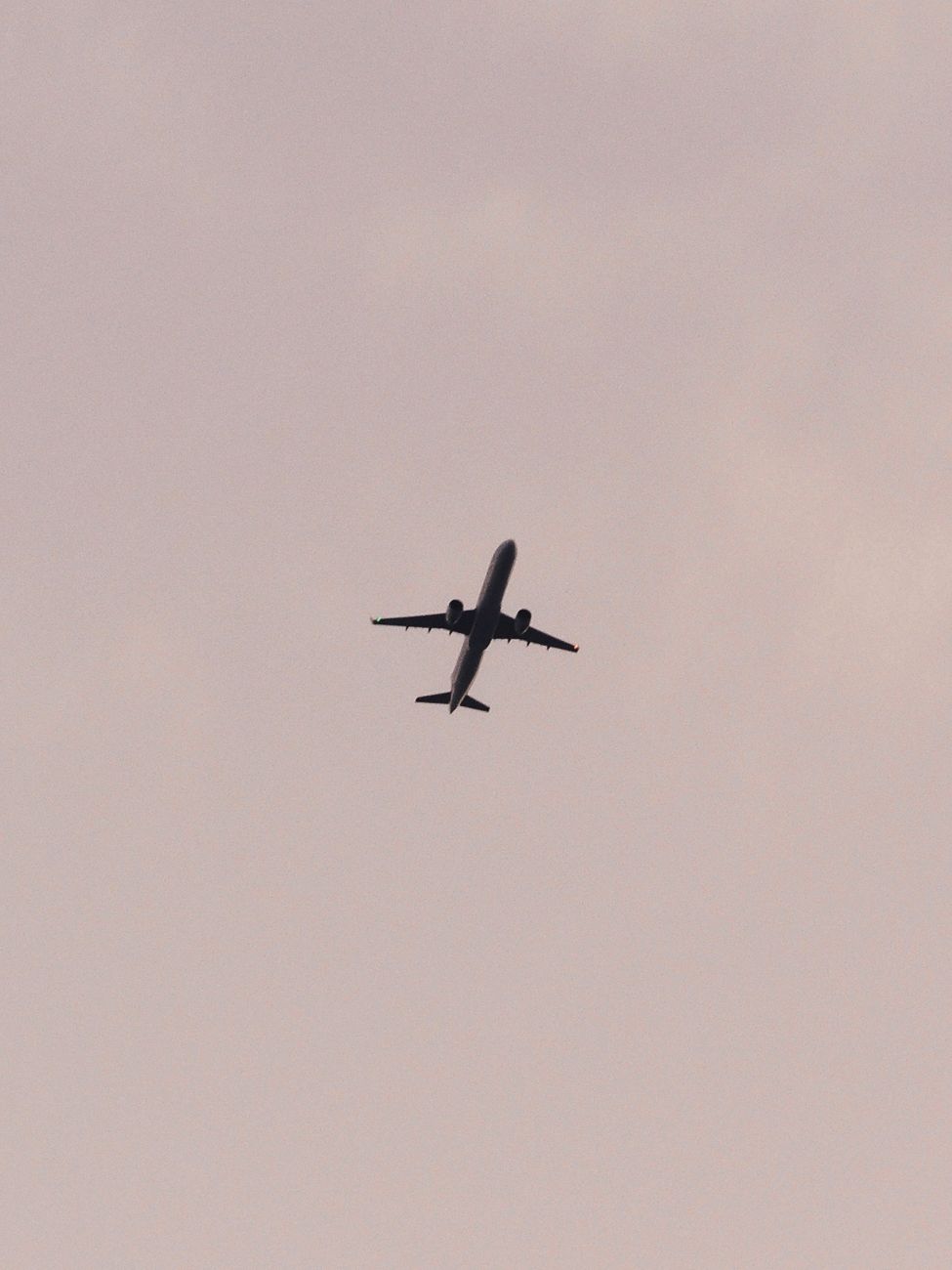 A commercial airplane silhouette captured flying against a cloudy sky, symbolizing travel and aviation.