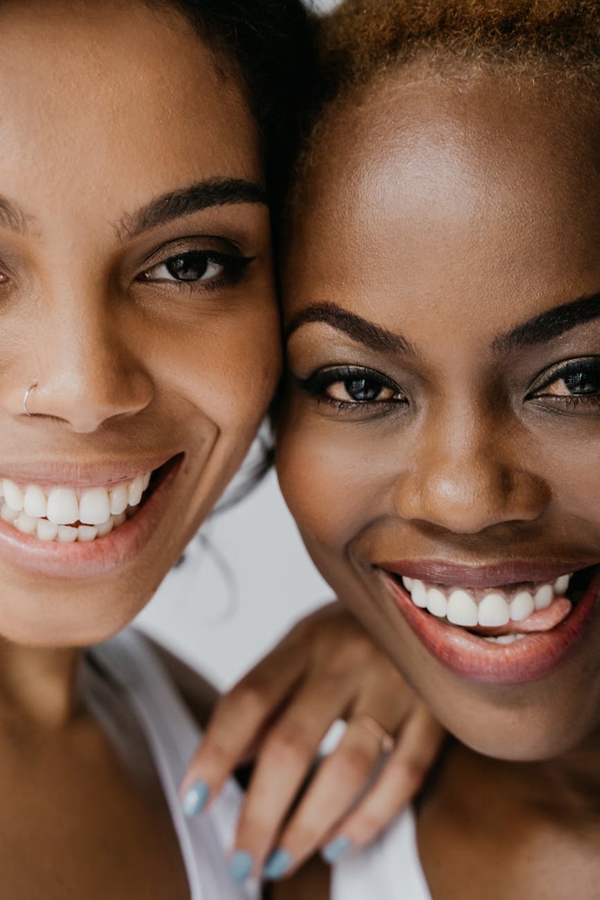 Portrait of two smiling women closely embracing each other, showcasing friendship and happiness.