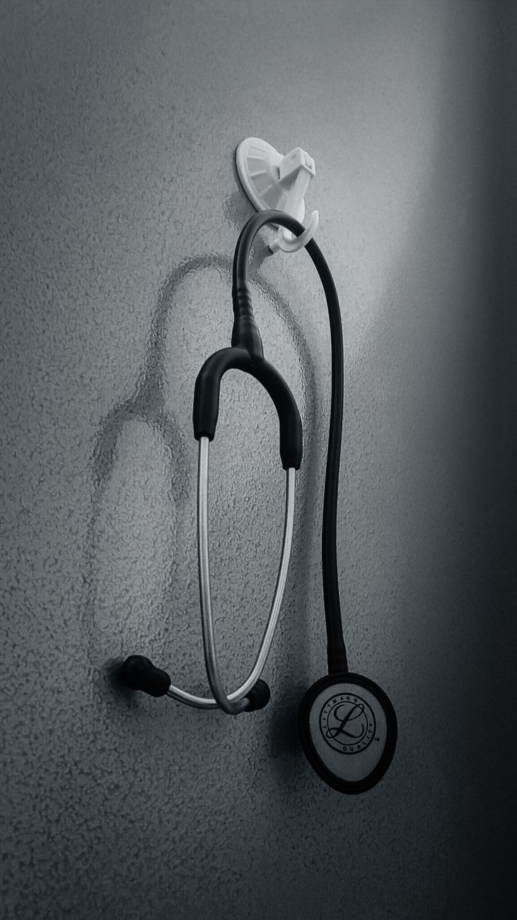 Monochrome image of a stethoscope hanging on a wall, conveying a medical theme.