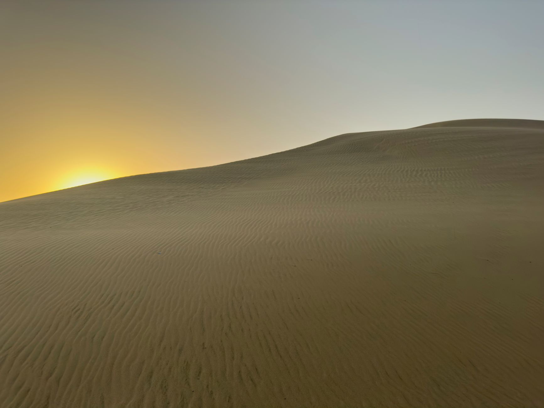 Peaceful sand dunes illuminated by the rising sun, showcasing nature's beauty in the desert.