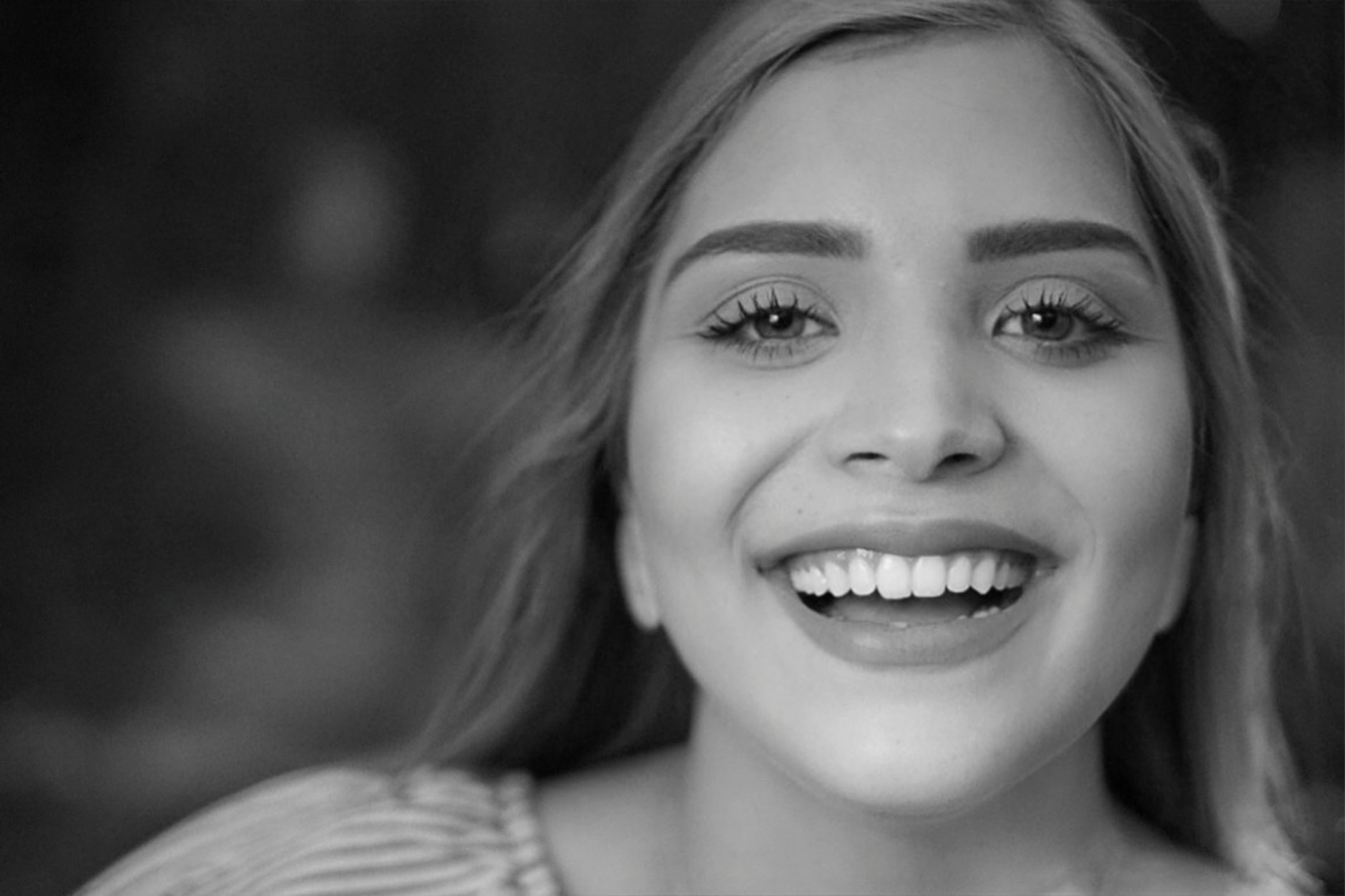 Close-up black and white portrait of a smiling woman looking directly at the camera.