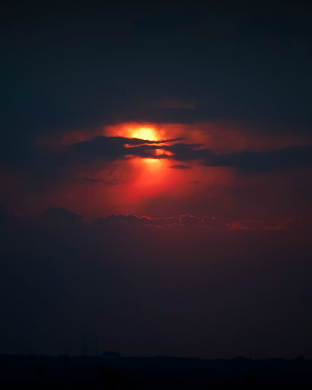 A vivid sunset with dramatic clouds casting a fiery glow over the landscape.
