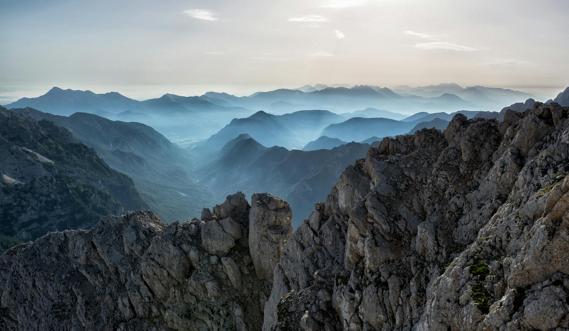 Capture of a tranquil mountain range at dawn with misty valleys and rocky peaks.