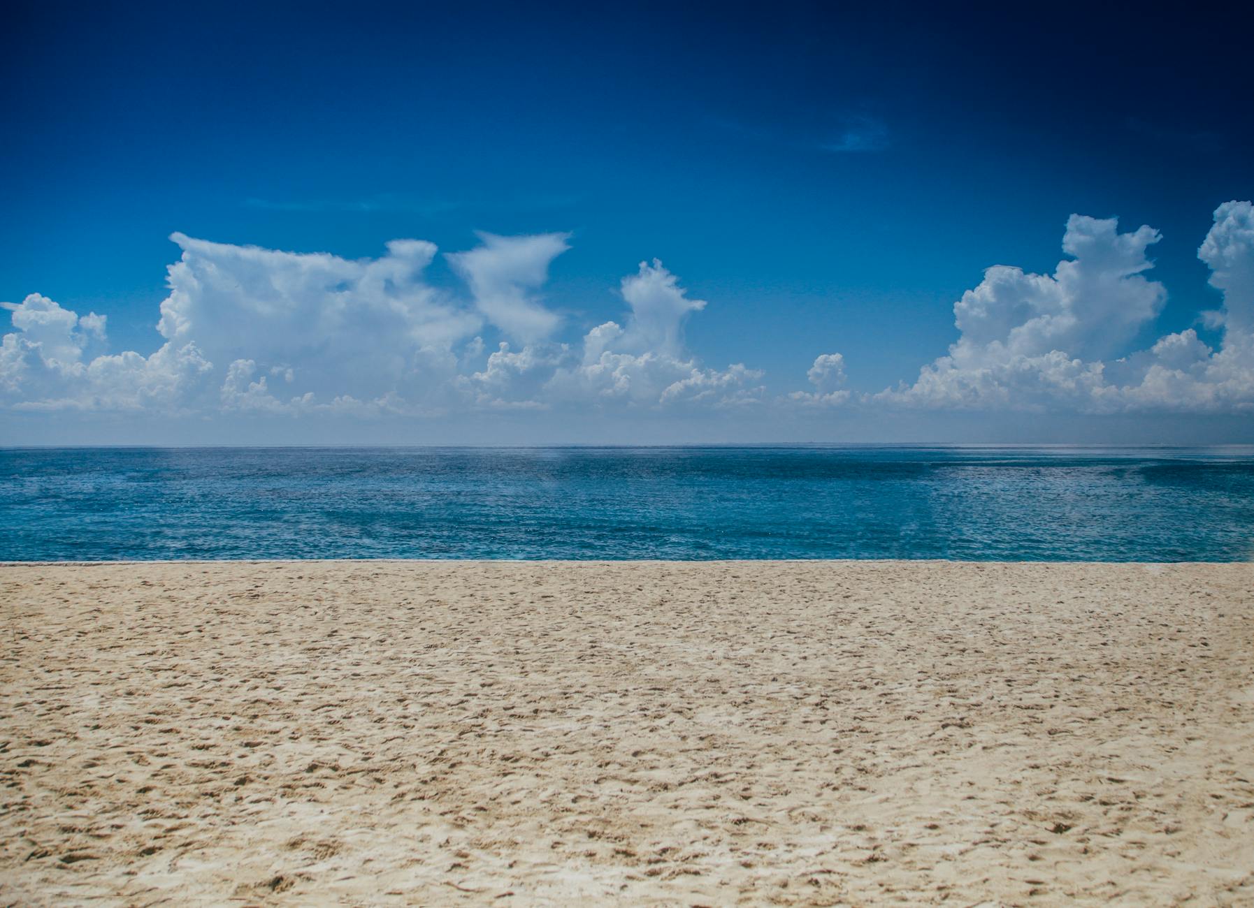 A tranquil beach scene with clear skies and gentle ocean waves, perfect for relaxation.