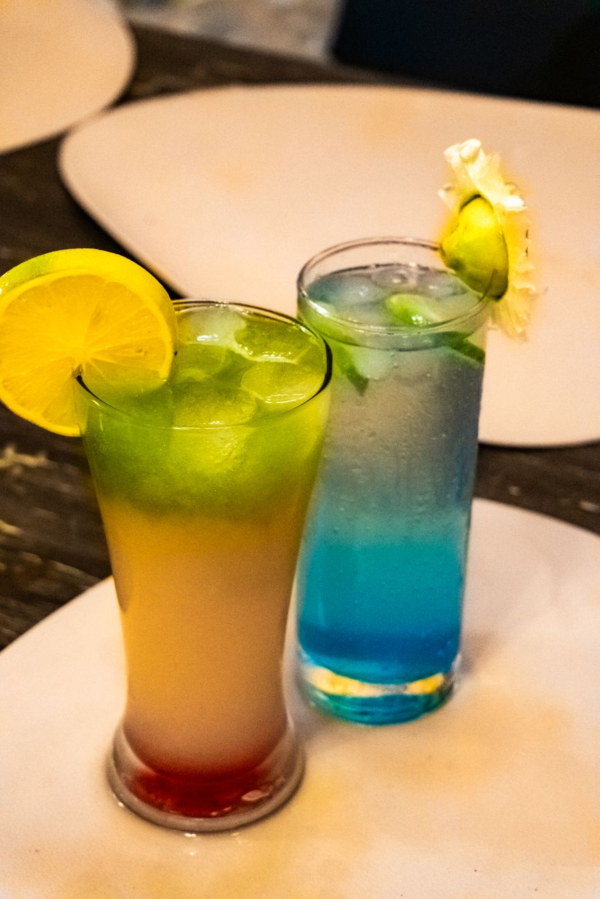 Colorful tropical cocktails with lemon and lime garnishes on a table.