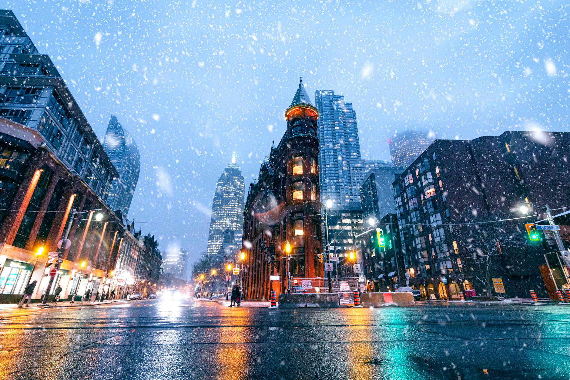 A captivating snow-covered street view of Toronto's iconic Gooderham Building at dusk.