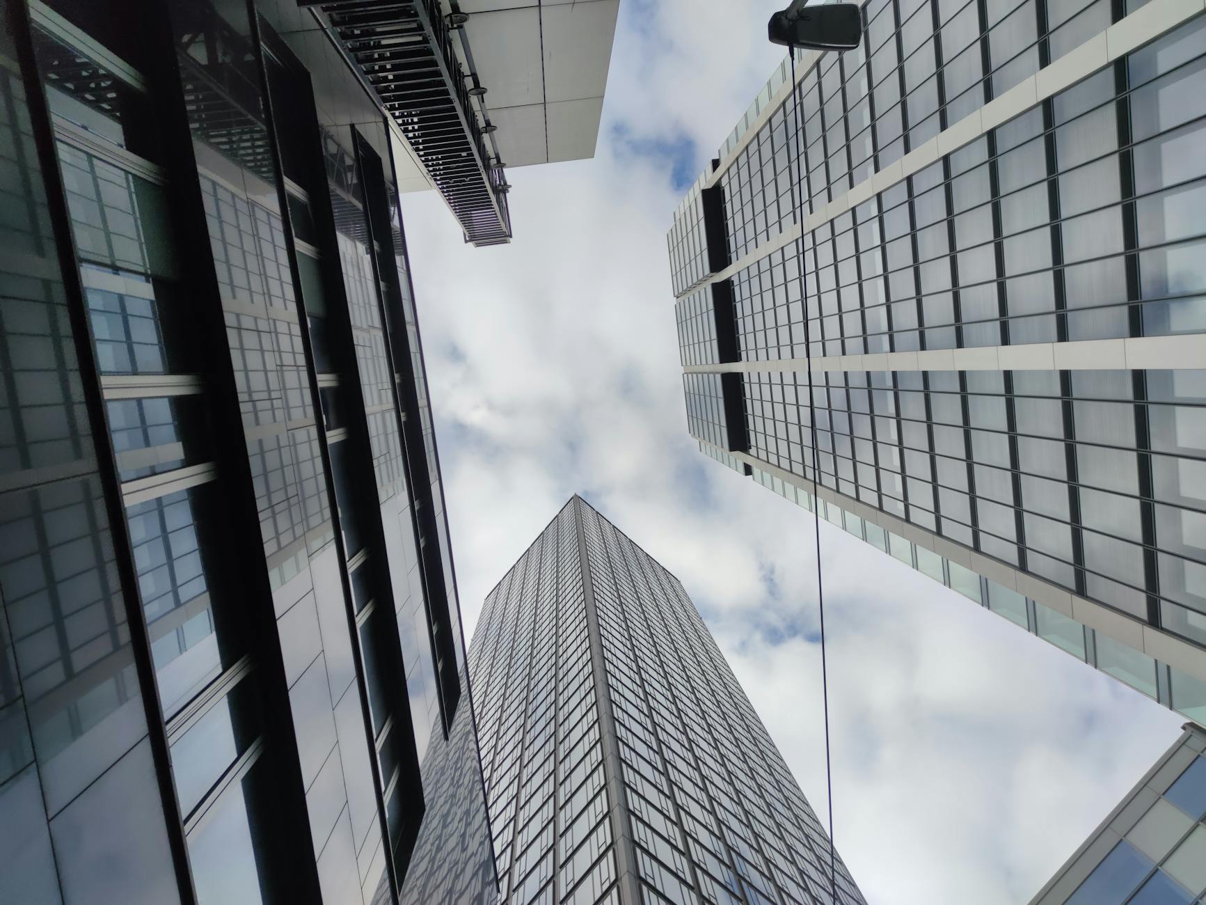 Dynamic low-angle view of modern skyscrapers in Frankfurt against a cloudy sky.